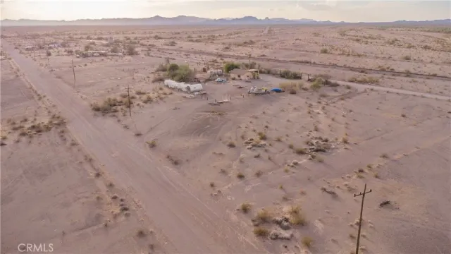 a view of a dry field with trees in the background
