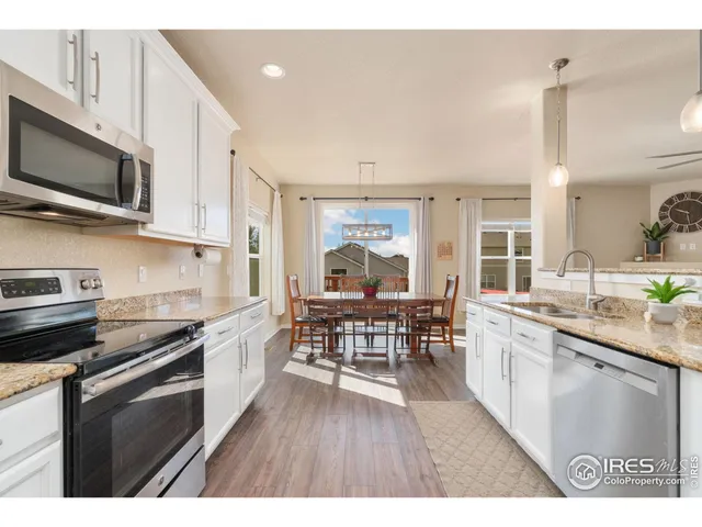 a kitchen with stainless steel appliances a microwave a stove a sink dishwasher a microwave oven with white cabinets and wooden floor