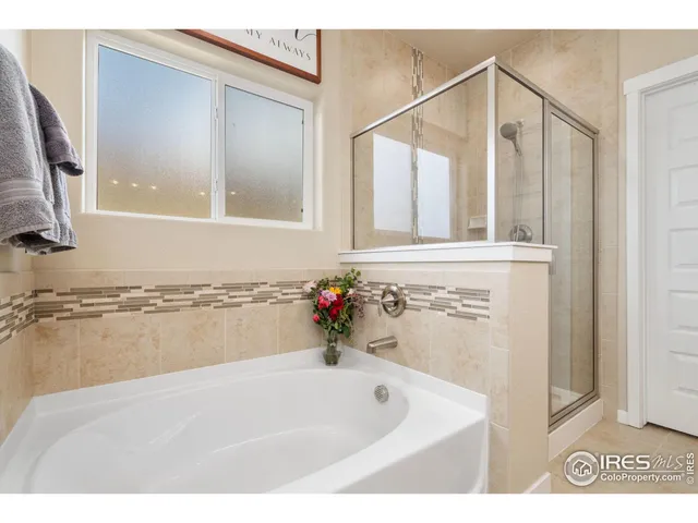 a bathroom with a tub a mirror and a shower