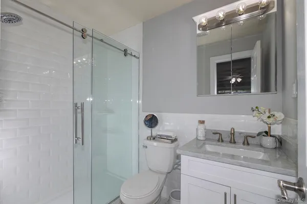 a bathroom with a granite countertop sink a toilet and shower