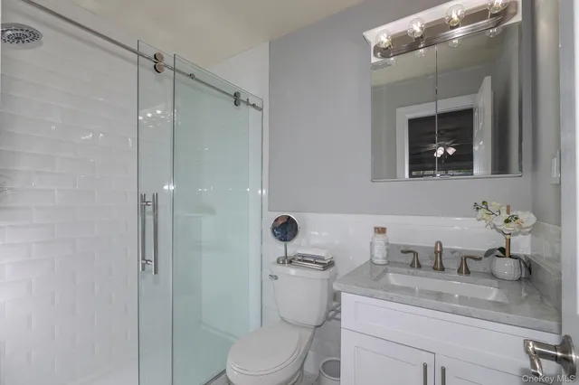 a bathroom with a granite countertop sink a toilet and shower