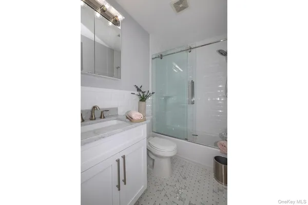 a bathroom with a granite countertop sink toilet and shower
