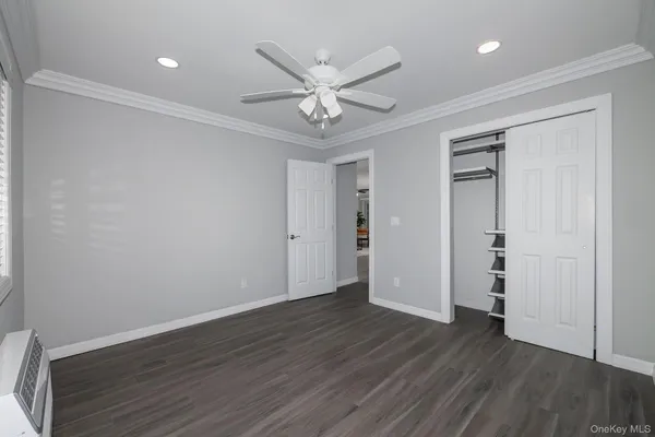 an empty room with wooden floor ceiling fan and window
