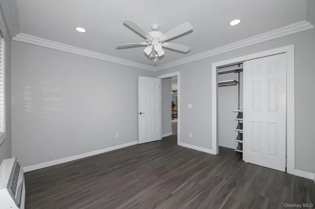 an empty room with wooden floor ceiling fan and window