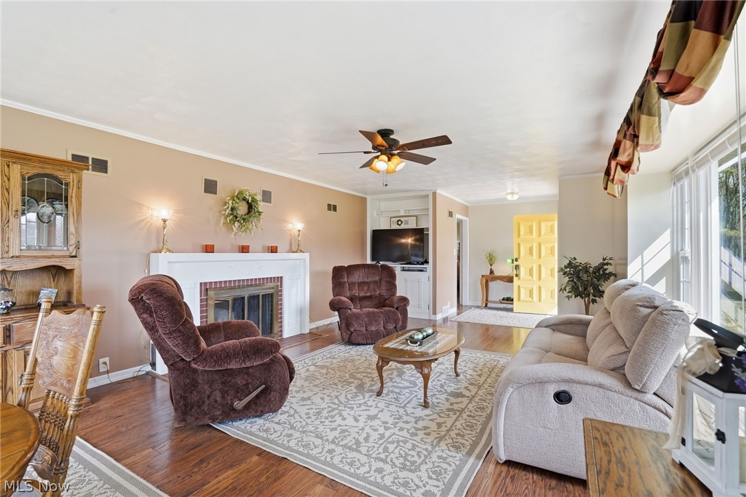 6655 Ceramic Road Crooksville, OH 43731 - Photo 12 of 34 Living room featuring a brick fireplace, wood finished floors, ornamental molding, and ceiling fan