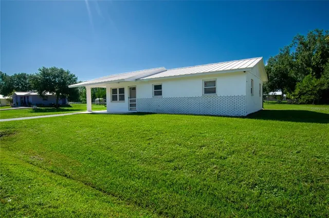 a view of a house next to a big yard and large trees