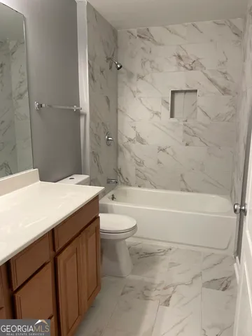 a bathroom with a granite countertop toilet a sink and bathtub