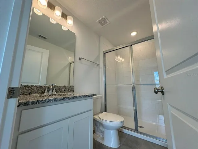 a bathroom with a granite countertop sink toilet and shower