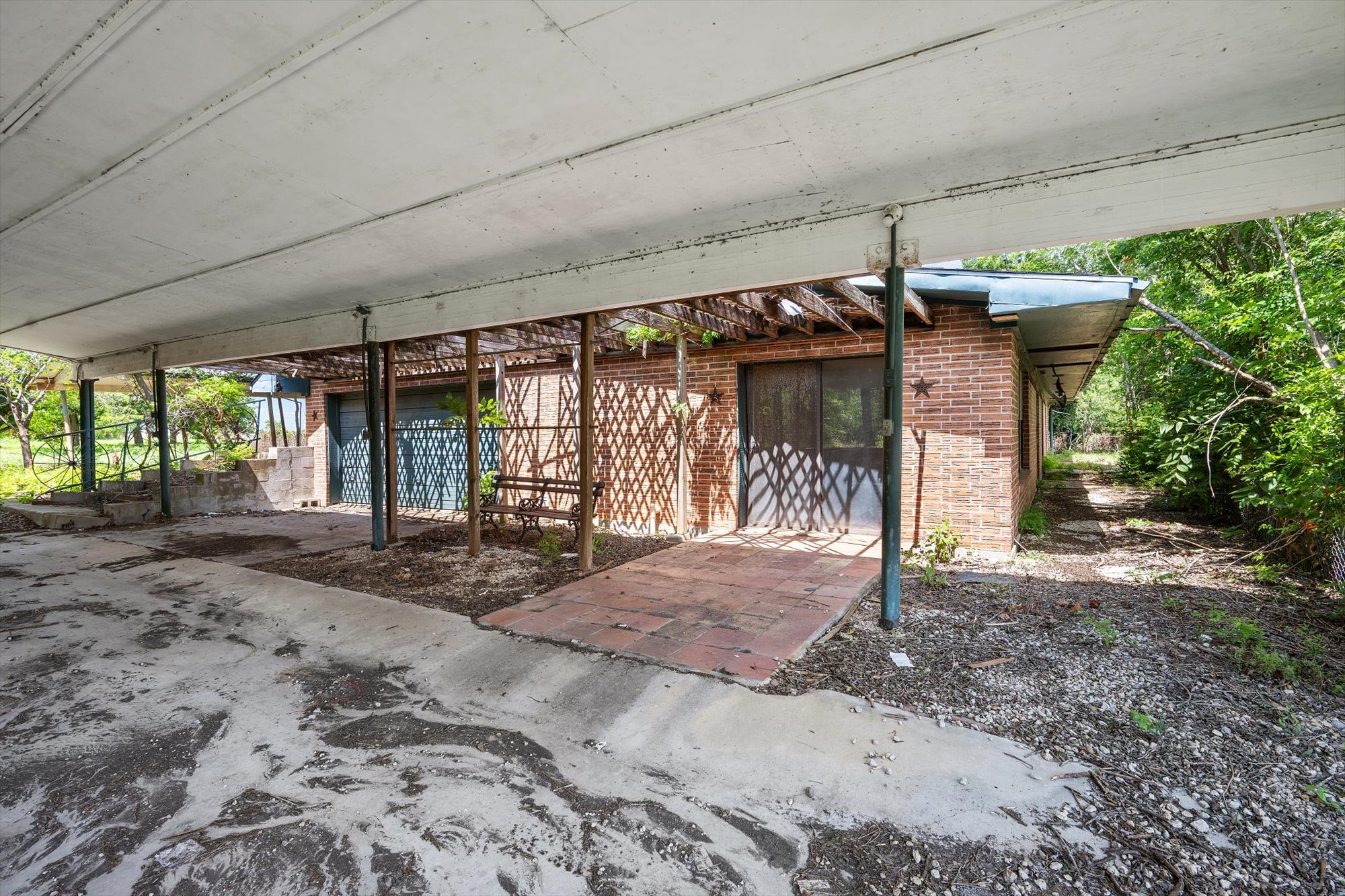 14201 Lund - Carlson Road Coupland, TX 78615 - Photo 39 of 40 A spacious carport offers covered parking next to a charming brick-faced structure and verdant landscaping.