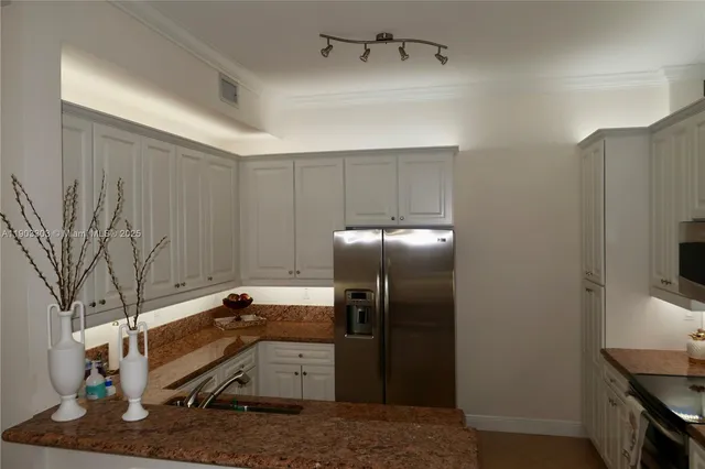 a kitchen with stainless steel appliances kitchen island granite countertop a refrigerator a stove and a sink