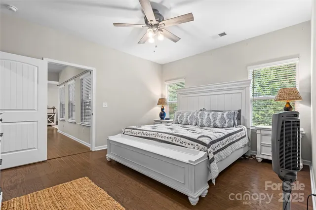 a white bed sitting in a bedroom next to a window with a chandelier