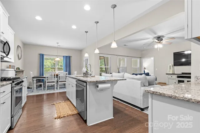 a large kitchen with kitchen island a stove a sink a dining table and chairs with wooden floor
