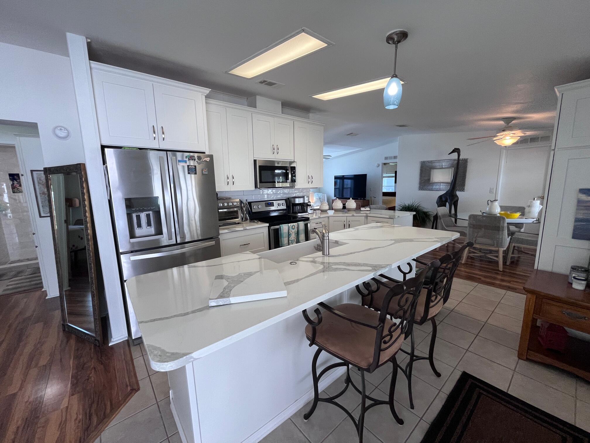 65 Turquoise Avenue Naples, FL 34114 - Photo 4 of 34 a kitchen with stainless steel appliances a refrigerator a stove a sink a dining table and chairs with wooden floor