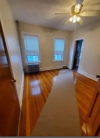 a view of an empty room with window and wooden floor