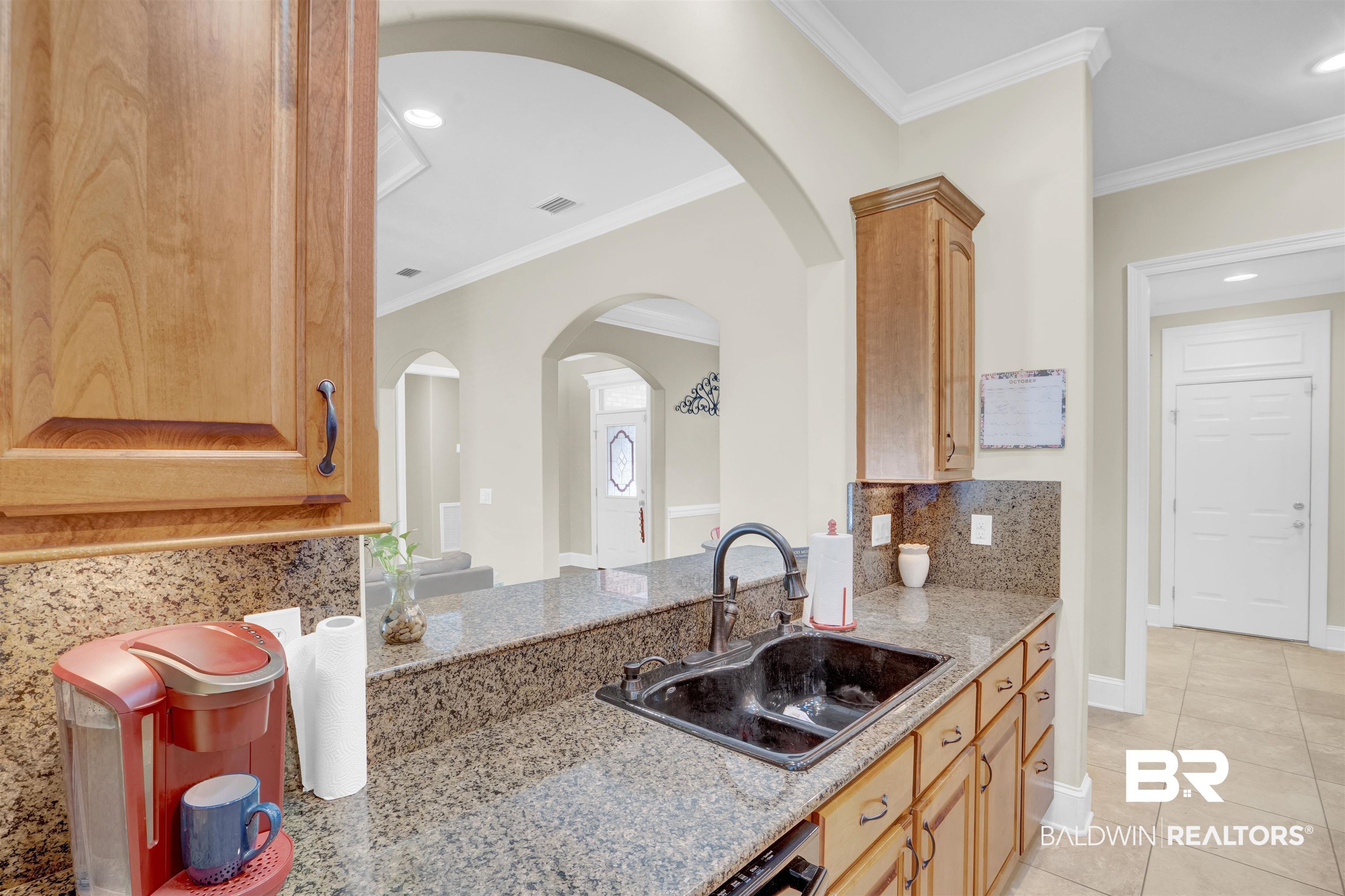 10951 Driver Court Fairhope, AL 36532 - Photo 21 of 46 Kitchen featuring light stone counters, sink, light tile patterned flooring, crown molding, and backsplash