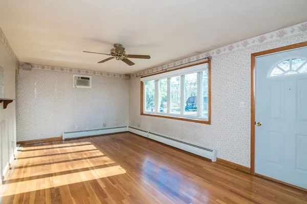 a view of an empty room with window and wooden floor