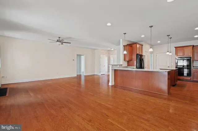 a view of a kitchen with kitchen island a sink wooden floor and a refrigerator