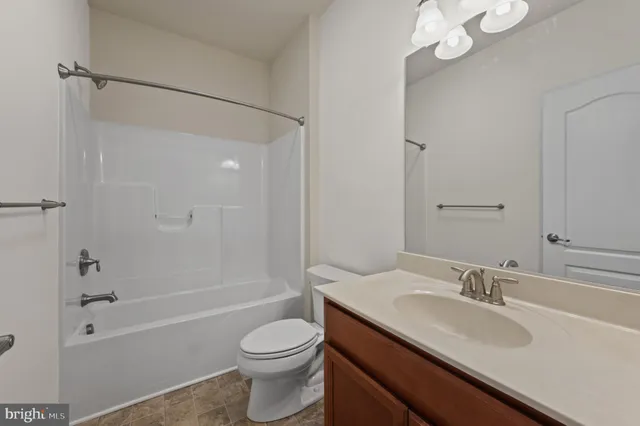 a bathroom with a granite countertop sink a toilet and shower