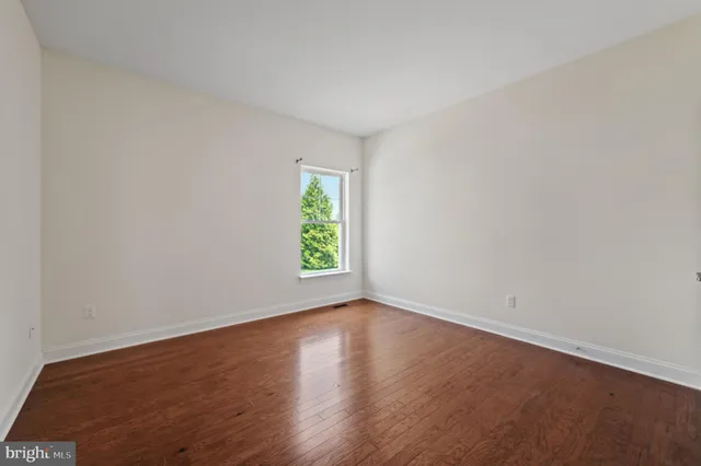 an empty room with wooden floor and window