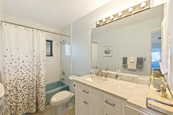 a bathroom with a granite countertop sink a toilet a mirror a vanity and shower