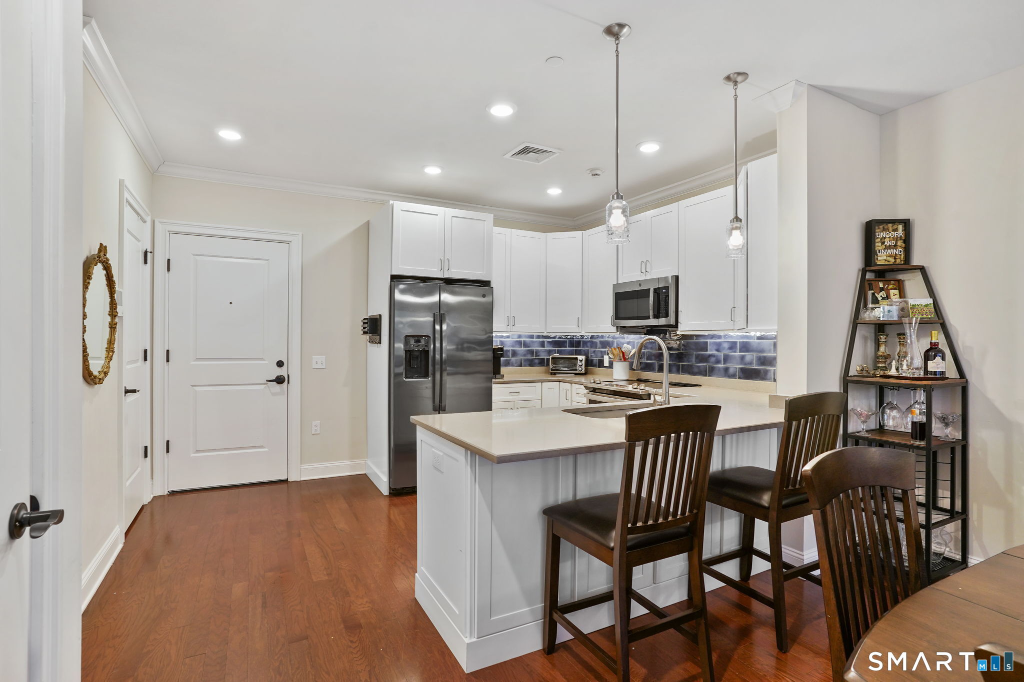 233 Danbury Road, Unit A209 Ridgefield, CT 06877 - Photo 6 of 25 a kitchen with stainless steel appliances a refrigerator a stove a sink dishwasher and a dining table with wooden floor