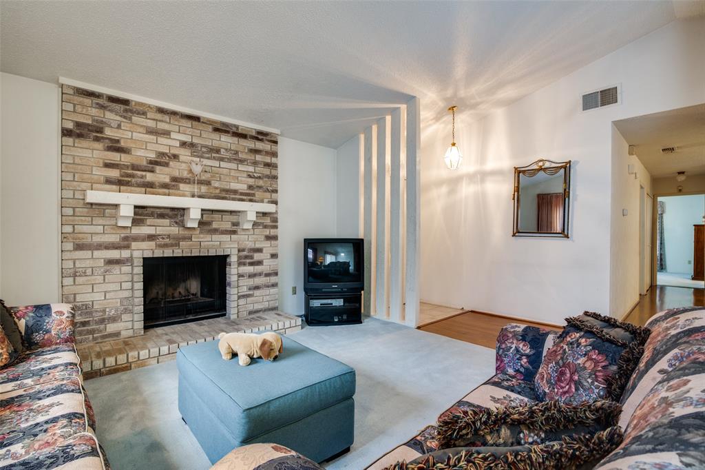 1916 Cobblestone Lane Garland, TX 75042 - Photo 12 of 33 Carpeted living room with a fireplace and vaulted ceiling