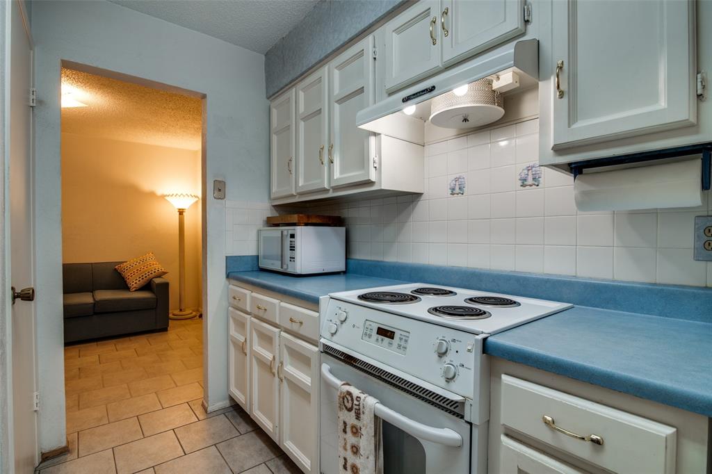 1916 Cobblestone Lane Garland, TX 75042 - Photo 19 of 33 Kitchen featuring white appliances, under cabinet range hood, decorative backsplash, light tile patterned flooring, and a textured ceiling