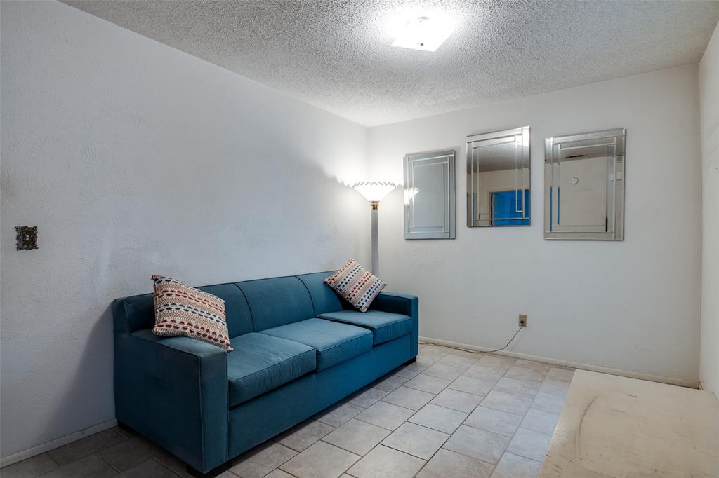1916 Cobblestone Lane Garland, TX 75042 - Photo 20 of 33 Living area featuring a textured ceiling, light tile patterned flooring, and baseboards