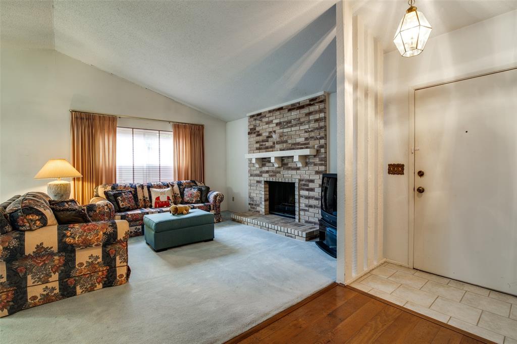 1916 Cobblestone Lane Garland, TX 75042 - Photo 9 of 33 Living room featuring lofted ceiling, wood finished floors, a fireplace, and a textured ceiling