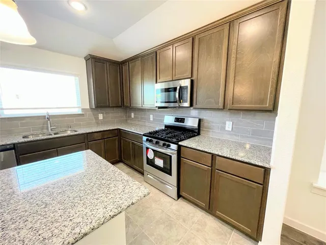 a kitchen with stainless steel appliances granite countertop wooden cabinets a stove top oven a sink and dishwasher