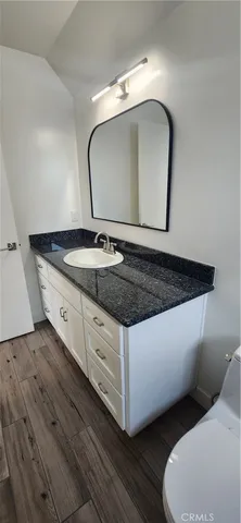 a bathroom with a granite countertop toilet a sink and a mirror