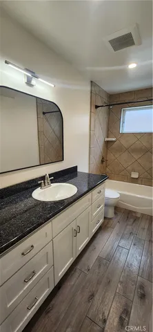a bathroom with a granite countertop sink a toilet and bathtub