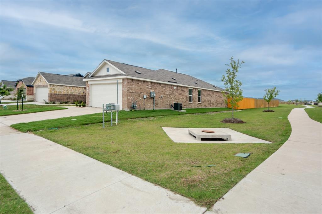 1419 Merlin Blf Street Forney, TX 75126 - Photo 3 of 24 Brick exterior featuring a two-car garage and a concrete pathway