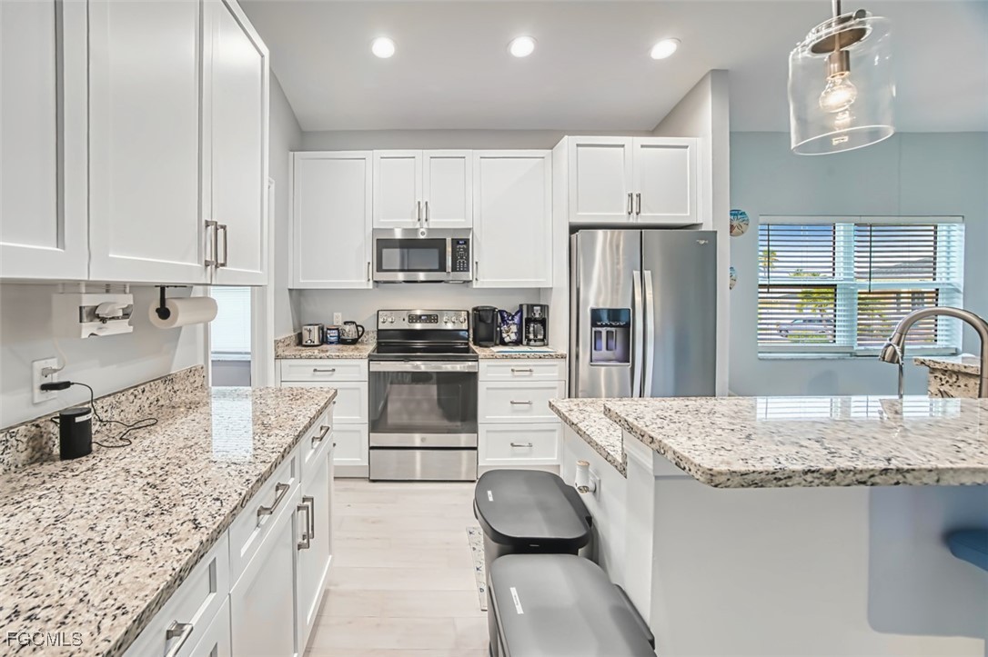 431 Lazy Way Fort Myers Beach, FL 33931 - Photo 18 of 40 a kitchen with granite countertop a stove sink and refrigerator