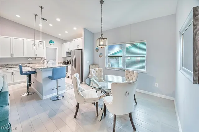 a dining room with kitchen island stainless steel appliances furniture a chandelier and a view of kitchen
