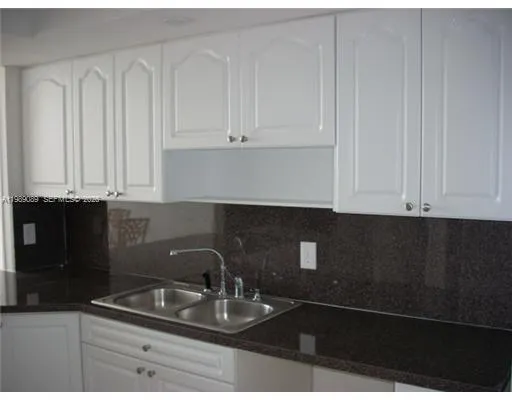 a kitchen with granite countertop white cabinets and sink