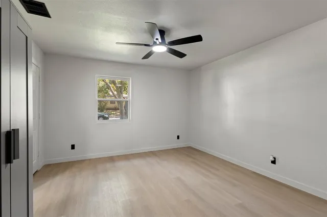 an empty room with a ceiling fan and window