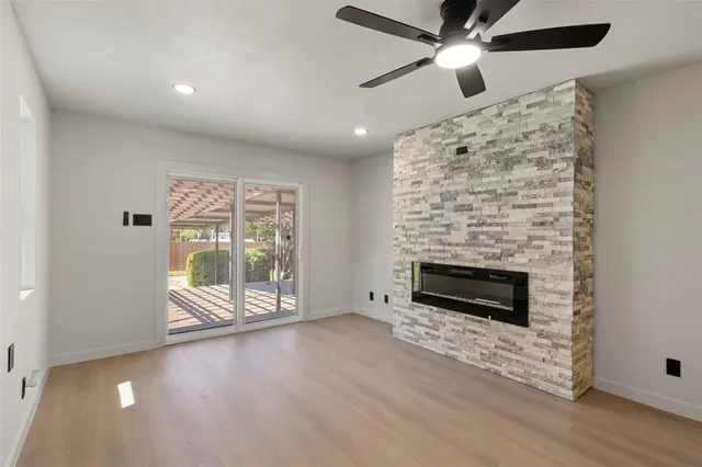 an empty room with windows fireplace and fan