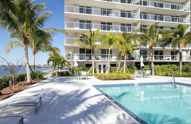 a view of a swimming pool with a house and trees in the background