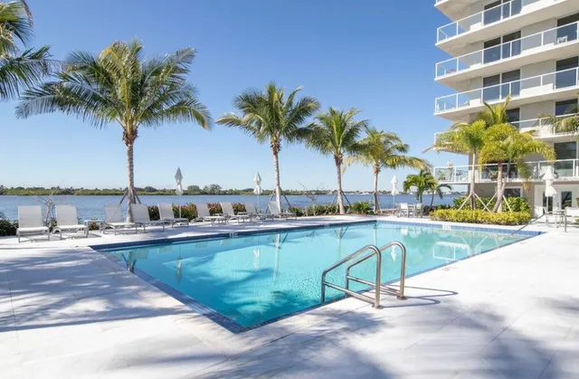 a view of a swimming pool with a chair and palm trees