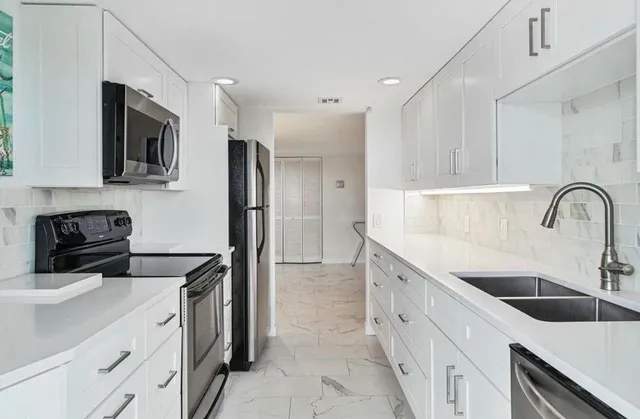 a kitchen with stainless steel appliances a sink a stove and a refrigerator with wooden floor