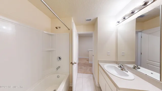 a bathroom with a tub sink and mirror