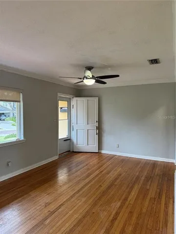 an empty room with wooden floor and windows