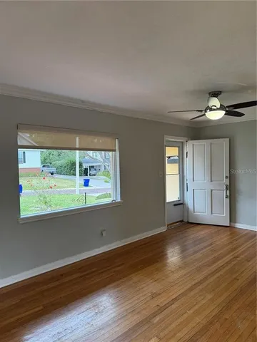 a view of an empty room with wooden floor and a window