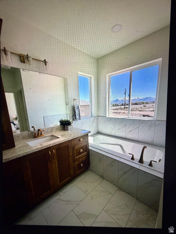 952 East Shilow Road, Unit 131 Erda, UT 84074 - Photo 12 of 12 Built-in tub with tile surround, a spacious vanity with an undermount sink, and two large windows