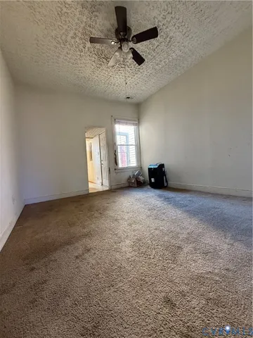 an empty room with windows and ceiling fan