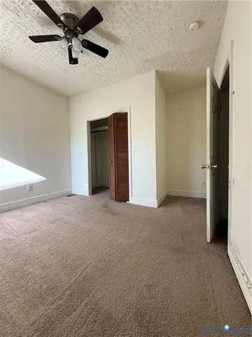 an empty room with a ceiling fan and window