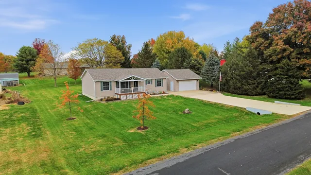 a aerial view of a house with yard and trees in the background