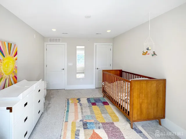 a bed room with a bed and a baby crib with wooden floor