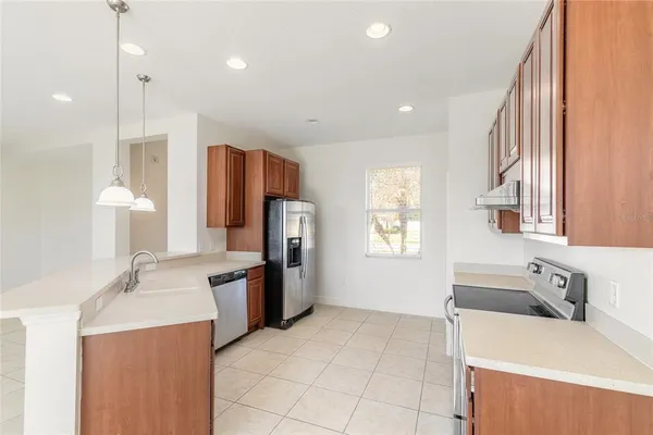 a kitchen with stainless steel appliances a stove a refrigerator and a sink with wooden cabinets